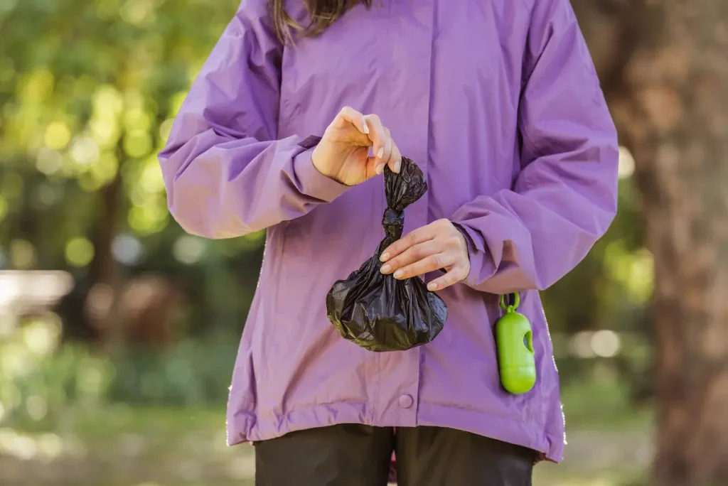 woman holding dog poop in bag wondering why it feels cold